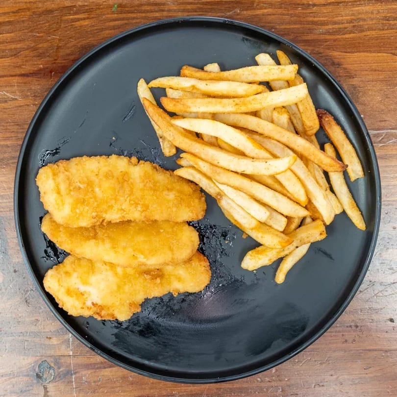 Three golden-fried chicken tenders and a pile of seasoned french fries on a black plate.